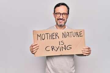 Middle age man asking for environment holding banner with mother nature is crying message looking positive and happy standing and smiling with a confident smile showing teeth