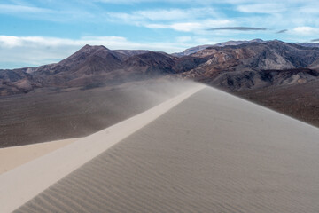 Strong wind blowing sand off the ridge of a sand dune, creating ripples, Eureka Dunes, Death Valley National Park, California