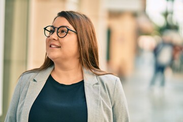 Young hispanic plus size businesswoman smiling happy standing at the city.