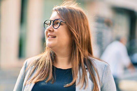 Young hispanic plus size businesswoman smiling happy standing at the city.