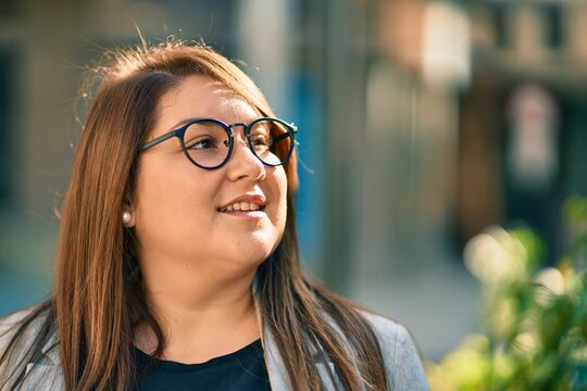 Young hispanic plus size businesswoman smiling happy standing at the city.