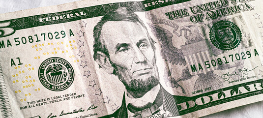 Dollar ( USD ). Money of United States of America. Five dollar bill in close-up with white...