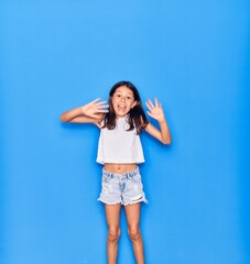 Fototapeta na wymiar Adorable hispanic child girl wearing casual clothes smiling happy. Jumping with smile on face over isolated blue background