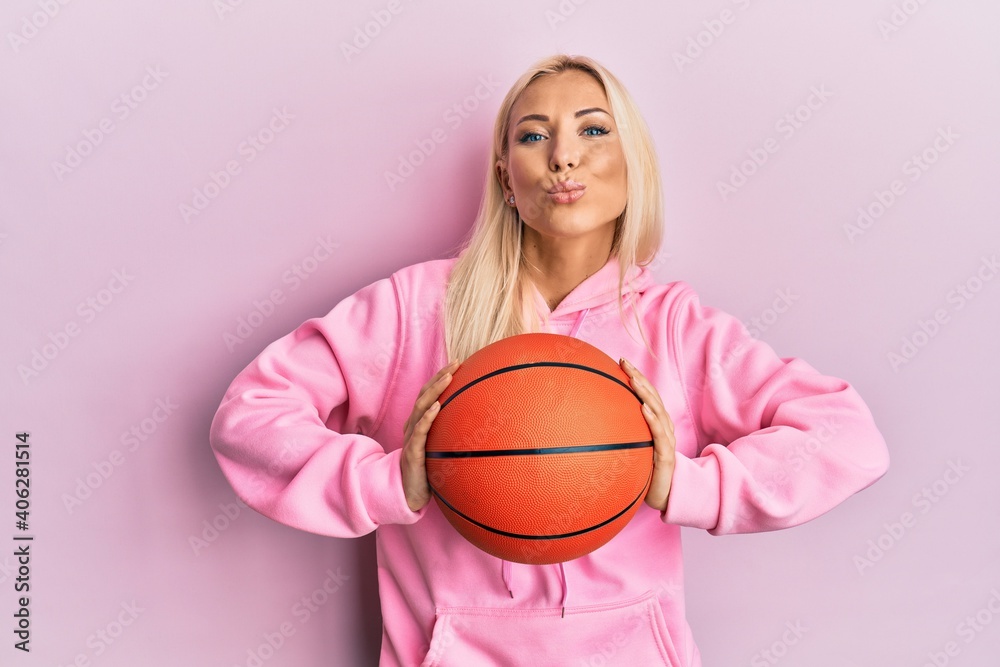 Canvas Prints young blonde woman holding basketball ball looking at the camera blowing a kiss being lovely and sex