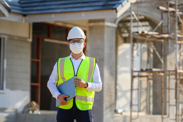 Foreman or young handsome Asian engineer Wear a helmet and a mask Control construction on the construction site