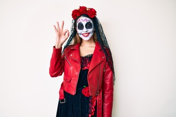 Woman wearing day of the dead costume over white smiling positive doing ok sign with hand and fingers. successful expression.