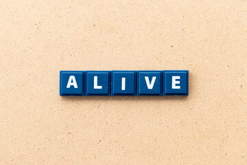 Tile alphabet letter in word alive on wood background