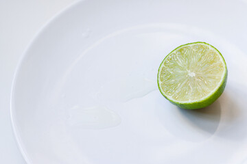 Sliced half of lime on plate in puddle of juice