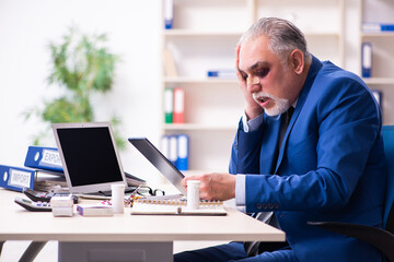 Old face injured employee sitting in the office
