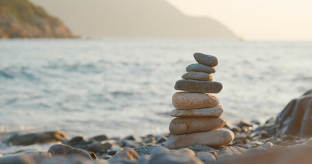 Balanced pebble pyramid on the beach at sunset