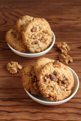 Oatmeal cookies with walnuts and raisins on small saucers standing on a wooden table. Closeup