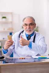 Old male doctor writing prescription in the clinic