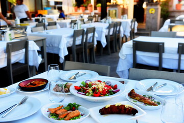 Served white holiday table on empty restaurant. Cutlery, crockery, glasses, plate, fork. Salads and meal. a dish with spoon, fork and knife on white table.
