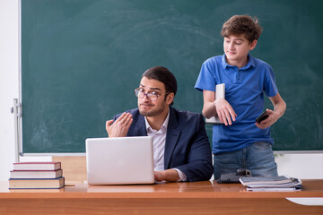 Young male teacher and schoolboy in the classroom