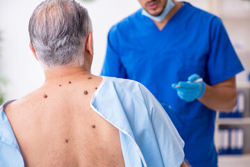 Obraz premium Old man visiting young male doctor dermatologist