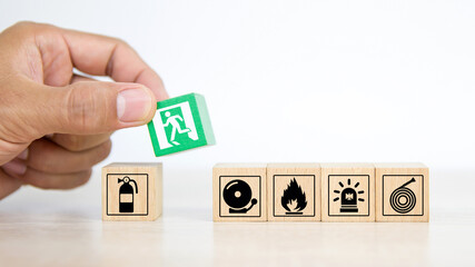 Close-up hand choose a wooden toy blocks stacked with fire exit icon for fire safety protection concepts.