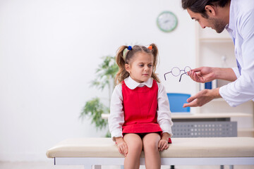 Small girl visiting young male doctor oculist