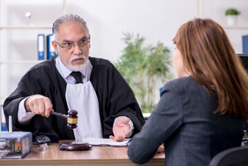 Old male judge and female client in the office