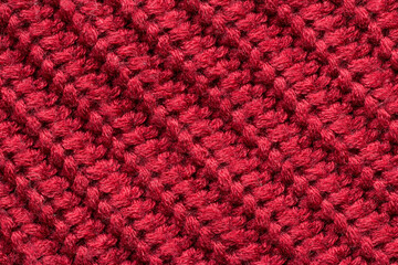 Red knitted fabric as an abstract texture. Knitting, elastic band pattern, English elastic band. Diagonal rows. Close-up. 