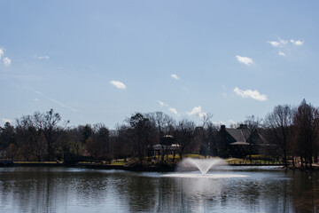 Landscaping. Fountain in a pond in a park in early spring on a bright sunny day. Cleveland Park in Spartanburg, SC, USA