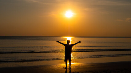 silhouette of man standing at beach at sunset.