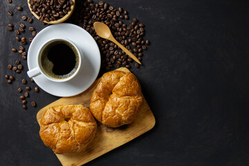 Breakfast / black coffee and croissants, roasted coffee beans on the table /  flat top view with copy space for your text.