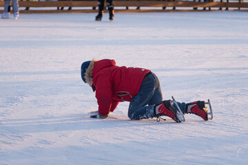 Fototapeta na wymiar Boy fell down while skating at ice rink. Sport trauma.