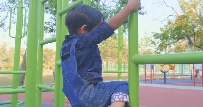 Adorable little boy climbing in playground of city park morning sunrise kid activity