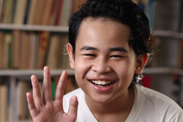 Happy cheerful Asian student boy smiling to camera, kid learning in library