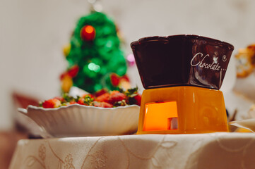 Chocolate fondue with fresh strawberries on the background of a Christmas tree. Christmas.