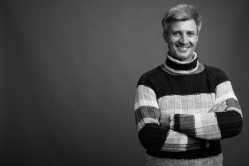 Man with blond hair wearing turtleneck sweater against gray background