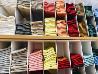 multicolored stacks of socks yellow, pink, gray, white, neatly stacked in wardrobe departments, clothes storage organization concept