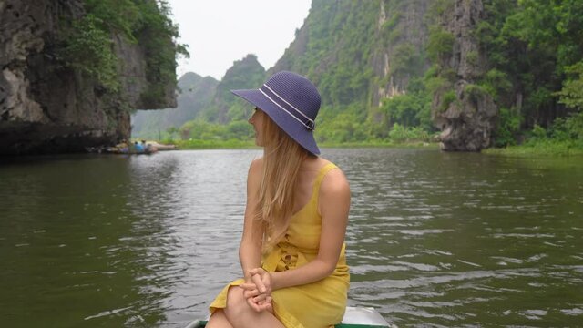 A young woman on a boat having a river trip among rocks in Ninh Binh, a tourist destination in northern Vietnam. Travel to Vietnam concept
