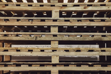 Stacked used wooden pallets in warehouse for industrial and transport. Stacks of Euro-type cargo pallets. Background of wooden pallet. Concept of warehousing and storage of goods. Copy space