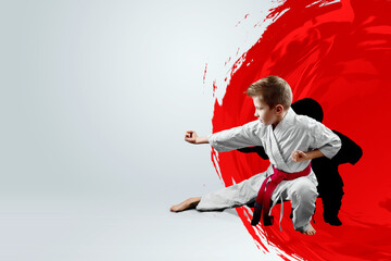A boy in a white kimono with a red belt against the background of a red circle, the sun. Karate...