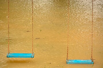 Playground swings with flooded ground and grass underneath