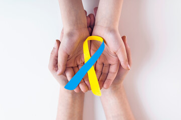 Blue yellow awareness ribbon on helping hand for World down syndrome day WDSD March 21 raising...
