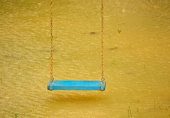 Playground swings with flooded ground and grass underneath