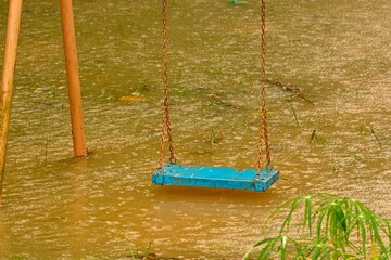 Playground swings with flooded ground and grass underneath