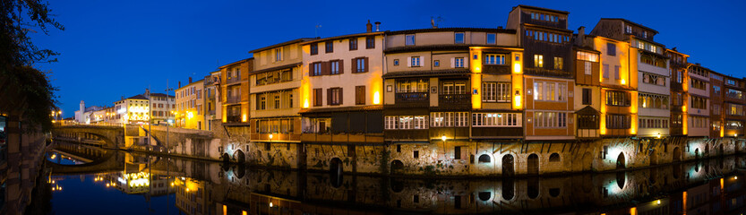 Scenic panoramic view of illuminated houses along Agout river in French city of Castres in twilight
