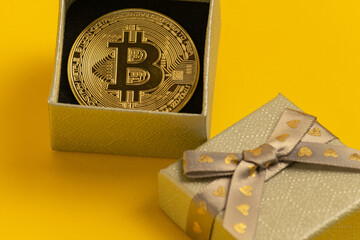 Golden bitcoin lies in a gift box, on a yellow background
