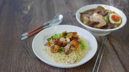 Set of Chinese noodle, a bowl of paste of rice flour over with pork egg and a plate of egg noodle with crispy pork