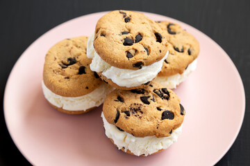 Homemade Chocolate Chip Cookie Ice Cream Sandwich on a pink plate on a black surface, low angle view. Close-up.