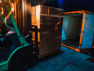 Worker driving forklift loading shipment carton boxes goods on wooden pallet at loading dock from...