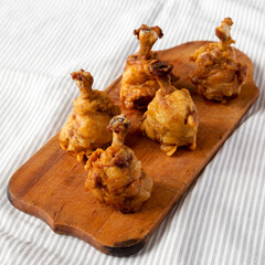 Homemade Spicy Chicken Lollipop on a rustic wooden board, side view.
