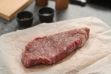 closeup raw seasoned new york steak on concrete countertop background