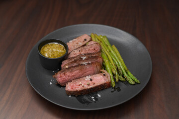 New york steak with asparagus on black plate with pesto