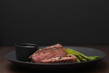 New york steak with asparagus on black plate with pesto