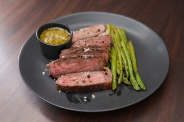 New york steak with asparagus on black plate with pesto