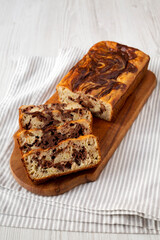 Homemade Chocolate Banana Bread on a rustic wooden board on a white wooden table, side view.